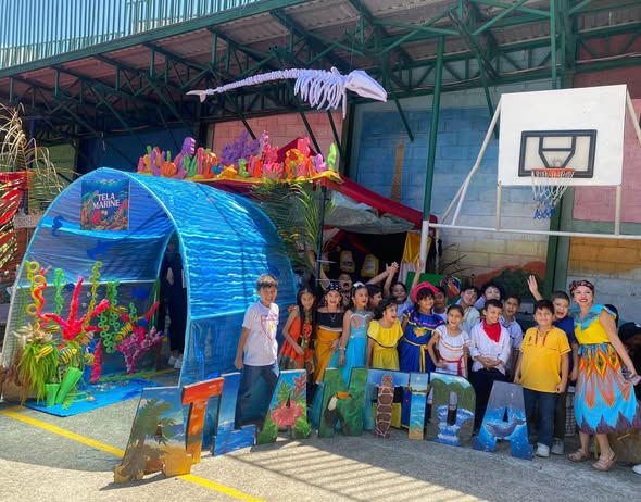 Students pose beside their Atlántida display at the AEIS cultural presentation